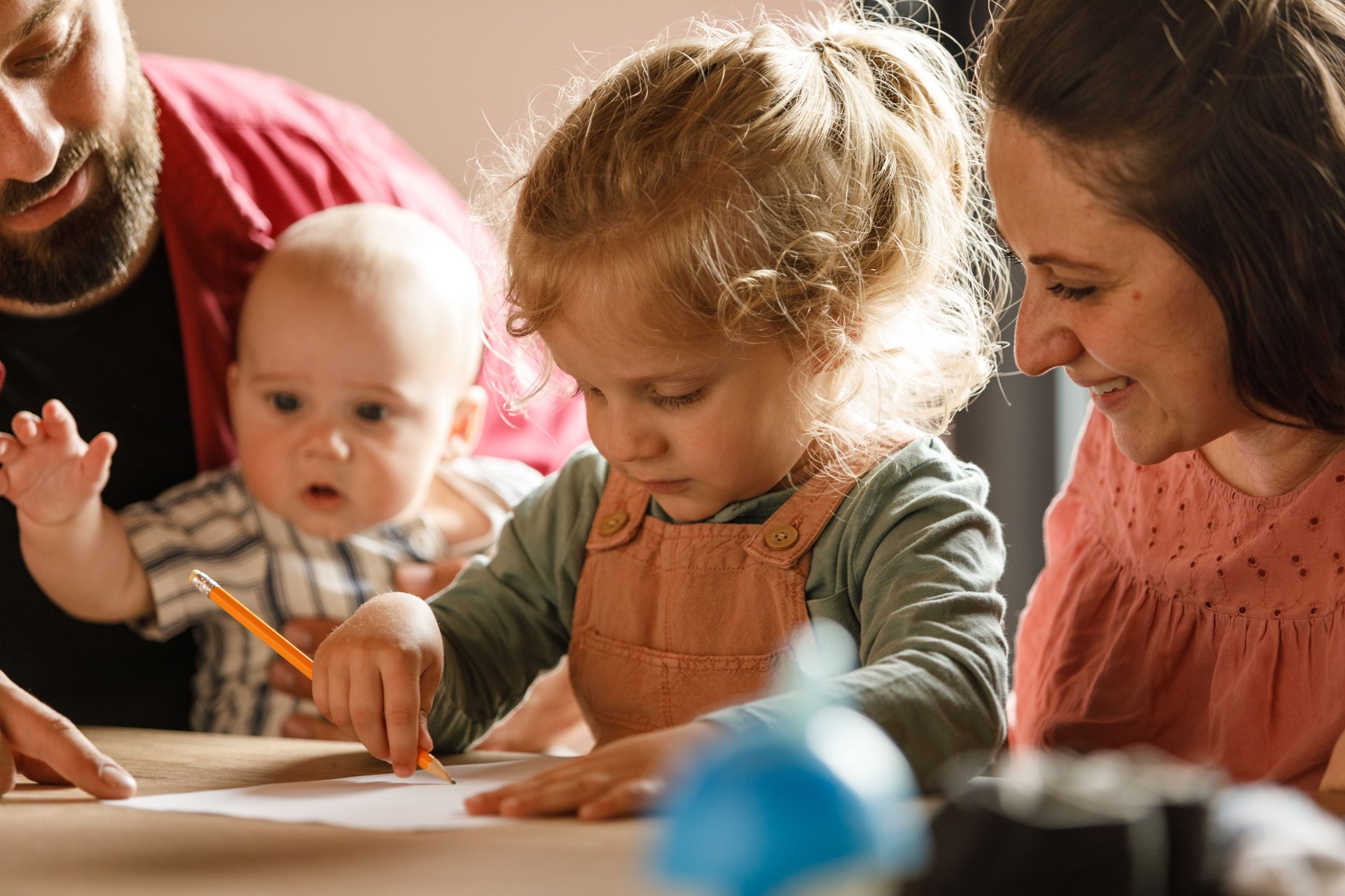 Toddler and his baby brother drawing with their parents